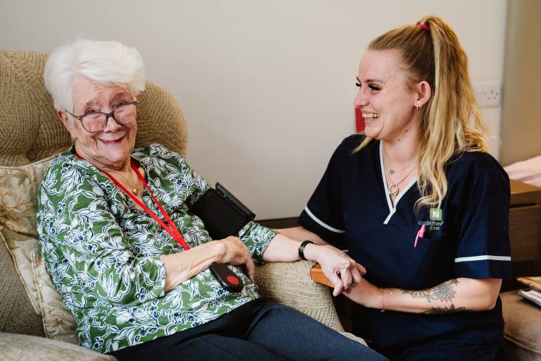 A social care worker taking the blood pressure of their client.