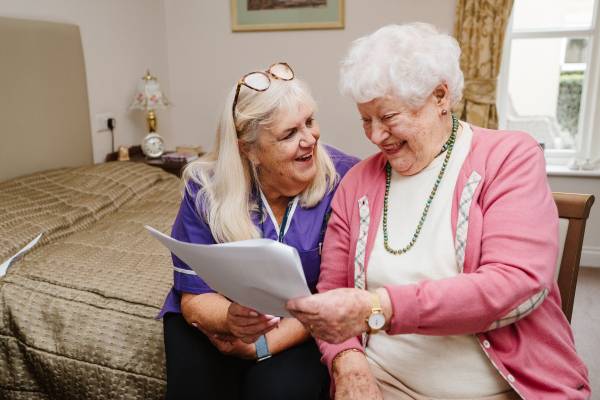 A care worker and an individual they support reading together happily